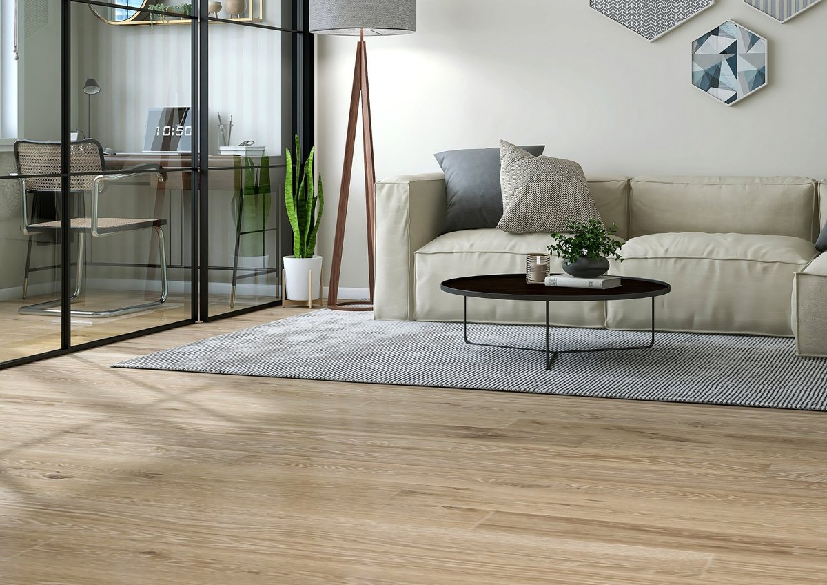 Modern living room with beige sofa, glass doors, wooden flooring, and minimalist decor including a coffee table and potted plants